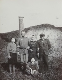 Rodina Bendů s rudoarmějcem, květen 1945. Zleva - sestra pamětníka Anna Bendová, neznámý sovětský voják, rodiče pamětníka, na zemi sedící pamětník Miroslav Benda