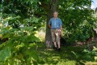 Antonín Najser in his garden in July 2024, behind the walnut tree there is a "threshing floor" where, according to his story, there is still buried ammunition from World War II