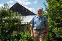 Antonín Najser in the garden of his house, in the background the barn built by his father