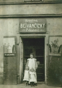 Grandmother Bejvančická in front of their family bakery in Plzeň; the witness's mother is at right and her sister at left