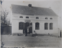 Family store with mixed goods in Svinaře, 1930 (The photo is probably the witness's grandmother Boučková and the boys are random customers, but the witness is not sure about the grandmother or the boys.)