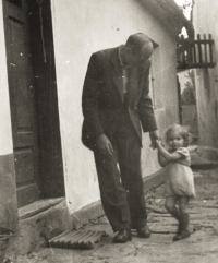 Father Stanislav Soudek with his daughter Rostislava Raidová in the backyard of his wife Anna's parents - at the butcher Jakub Fajka. The door leading to the sidehouse, in the background the gate to the stream. The photograph probably dates from 1944